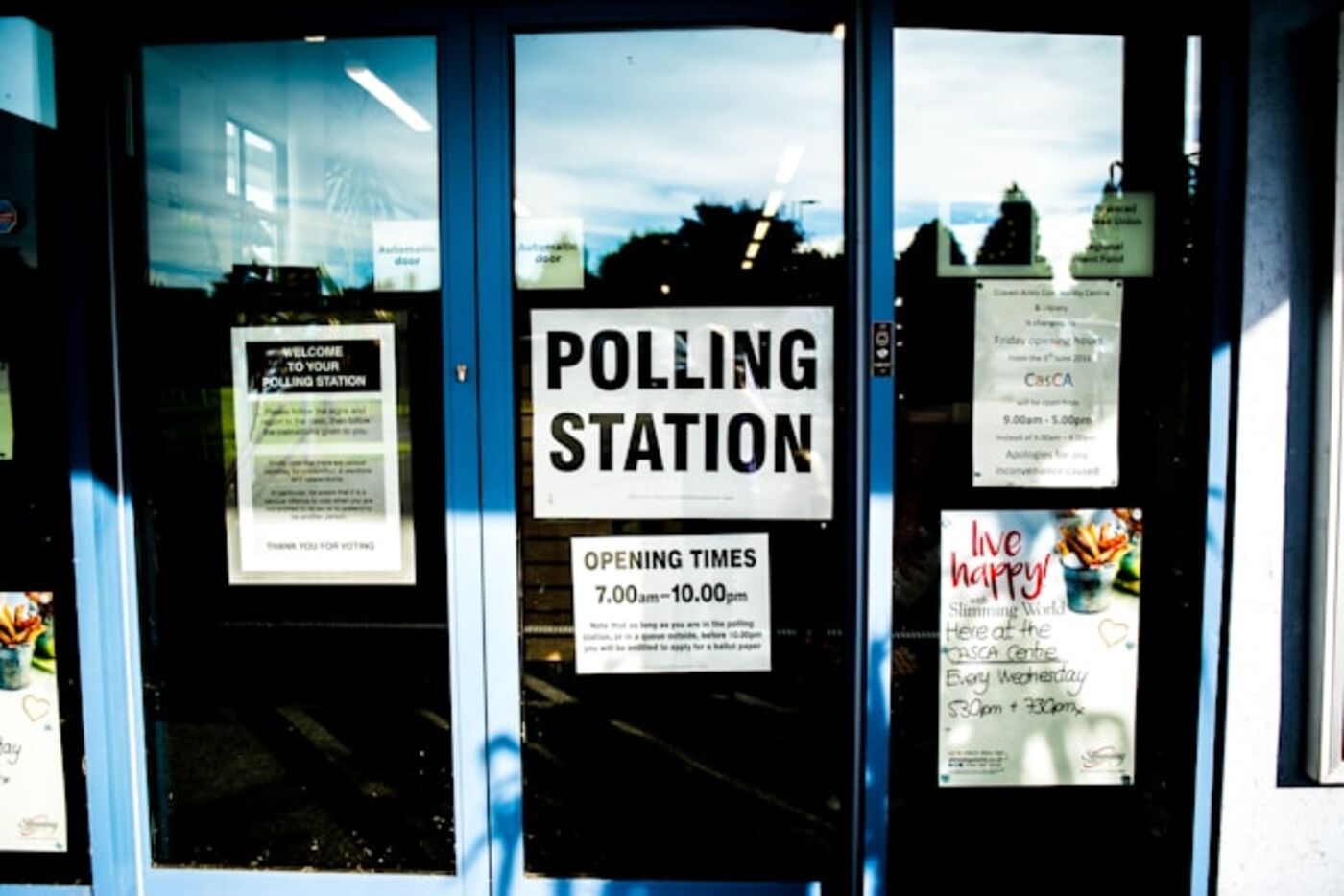 A polling station entrance with signs listing opening times